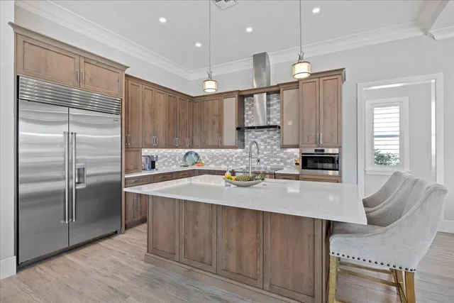 a kitchen with a stove a sink a kitchen island with chairs and wooden cabinets