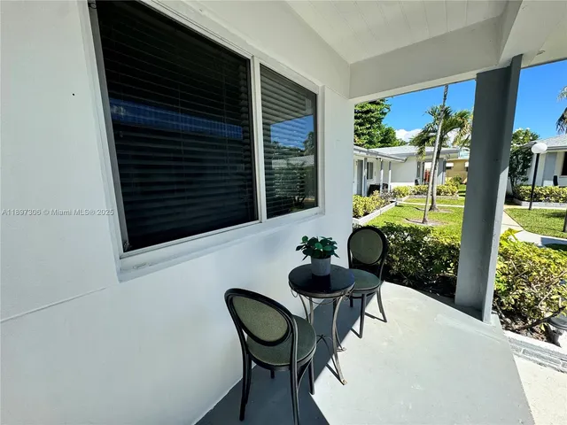 a backyard of a house with table and chairs and potted plants