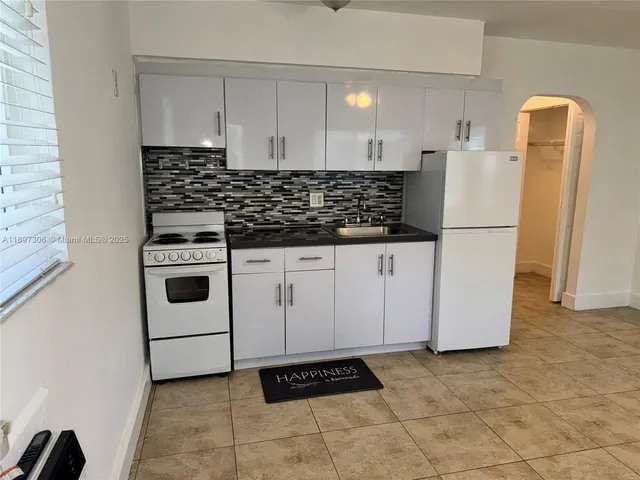 a white refrigerator freezer and a stove sitting inside of a kitchen