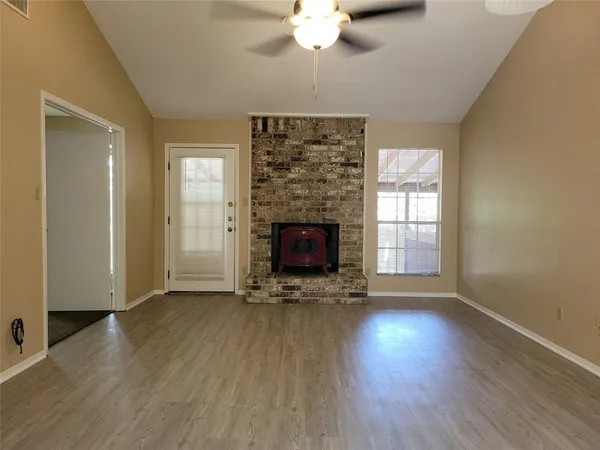 an empty room with wooden floor a fireplace and windows
