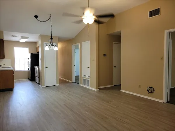 a view of an empty room with a window and wooden floor