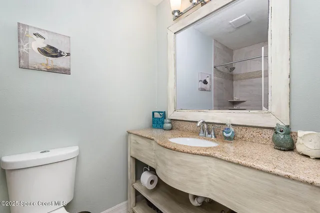 a bathroom with a granite countertop toilet sink and mirror