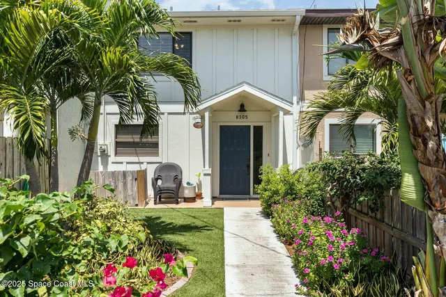 a front view of a house with a yard and potted plants