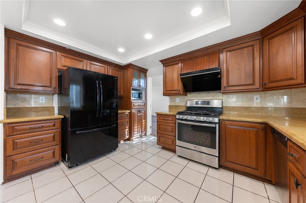 6598 Bradford Court Rancho Cucamonga, CA 91701 - Photo 22 of 48 a kitchen with granite countertop a refrigerator and a stove top oven