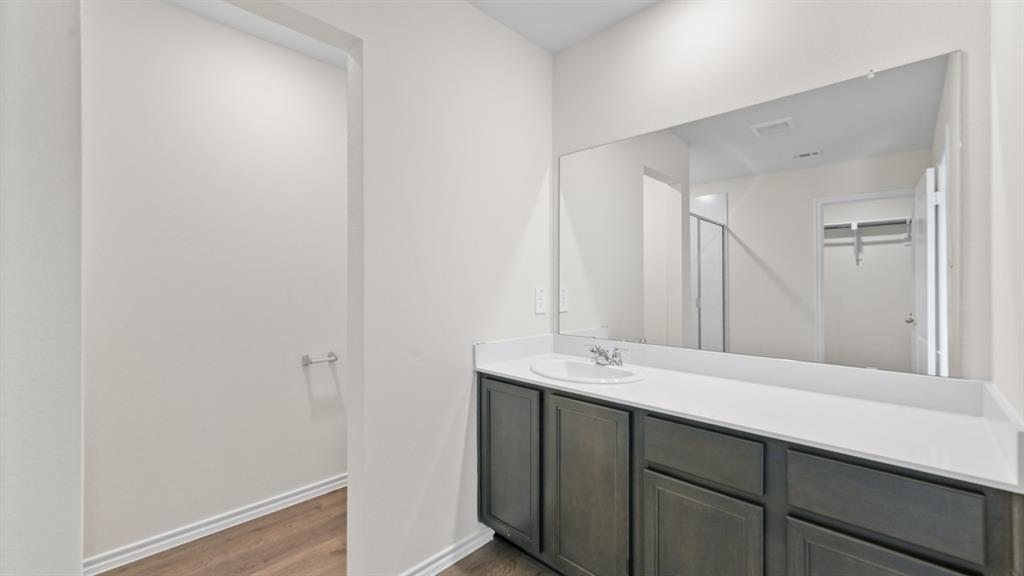 657 Glee Stem Road Lavon, TX 75166 - Photo 18 of 26 Vanity featuring a single undermount sink, a white countertop, and dark wood-finish cabinetry