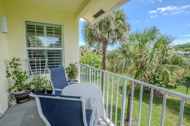 a view of a patio with table and chairs potted plants and floor to ceiling window