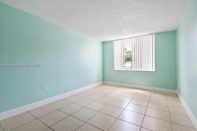 a view of an empty room with window and chandelier fan