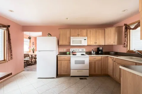 a kitchen with a refrigerator a stove top oven and white cabinets
