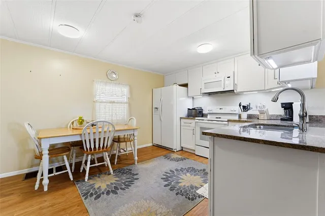 a kitchen with stainless steel appliances granite countertop a table chairs sink and cabinets
