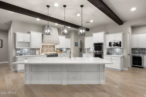 a large white kitchen with lots of counter space a sink appliances and cabinets