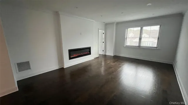 an empty room with wooden floor fire place and windows