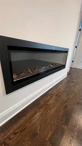 a view of an empty room with wooden floor and a fireplace