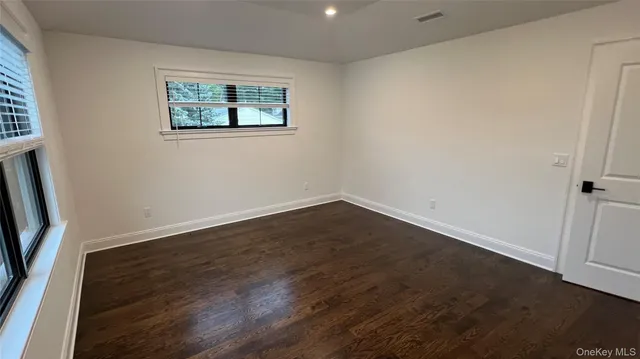 an empty room with wooden floor and window