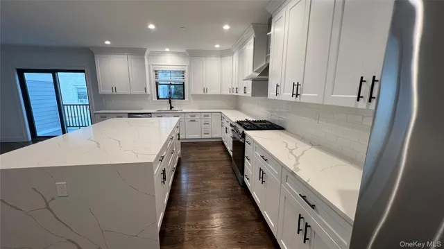 a large white kitchen with a sink and dishwasher a stove top oven with wooden floor