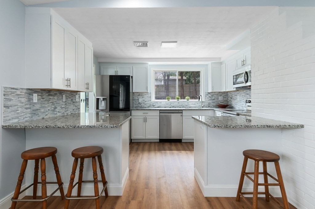 42 Amherst Road Beverly, MA 01915 - Photo 6 of 23 a kitchen with stainless steel appliances granite countertop a table chairs in it and wooden floors