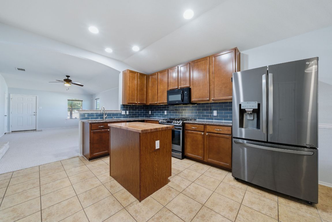 18153 Basket Flower Bend Elgin, TX 78621 - Photo 7 of 35 a kitchen with stainless steel appliances granite countertop a refrigerator and a stove top oven