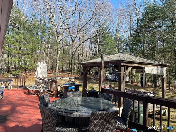 a view of patio with a table and chairs under an umbrella with a couch swing
