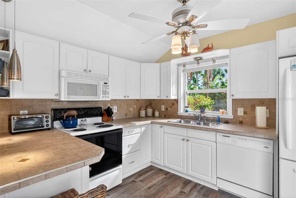 7152 Point Of Rocks Circle Sarasota, FL 34242 - Photo 80 of 88 a kitchen with a stove a sink a window and cabinets