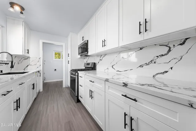 a kitchen with granite countertop a sink a stove refrigerator and cabinets