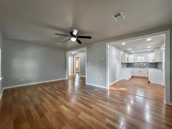 a view of an empty room and kitchen view
