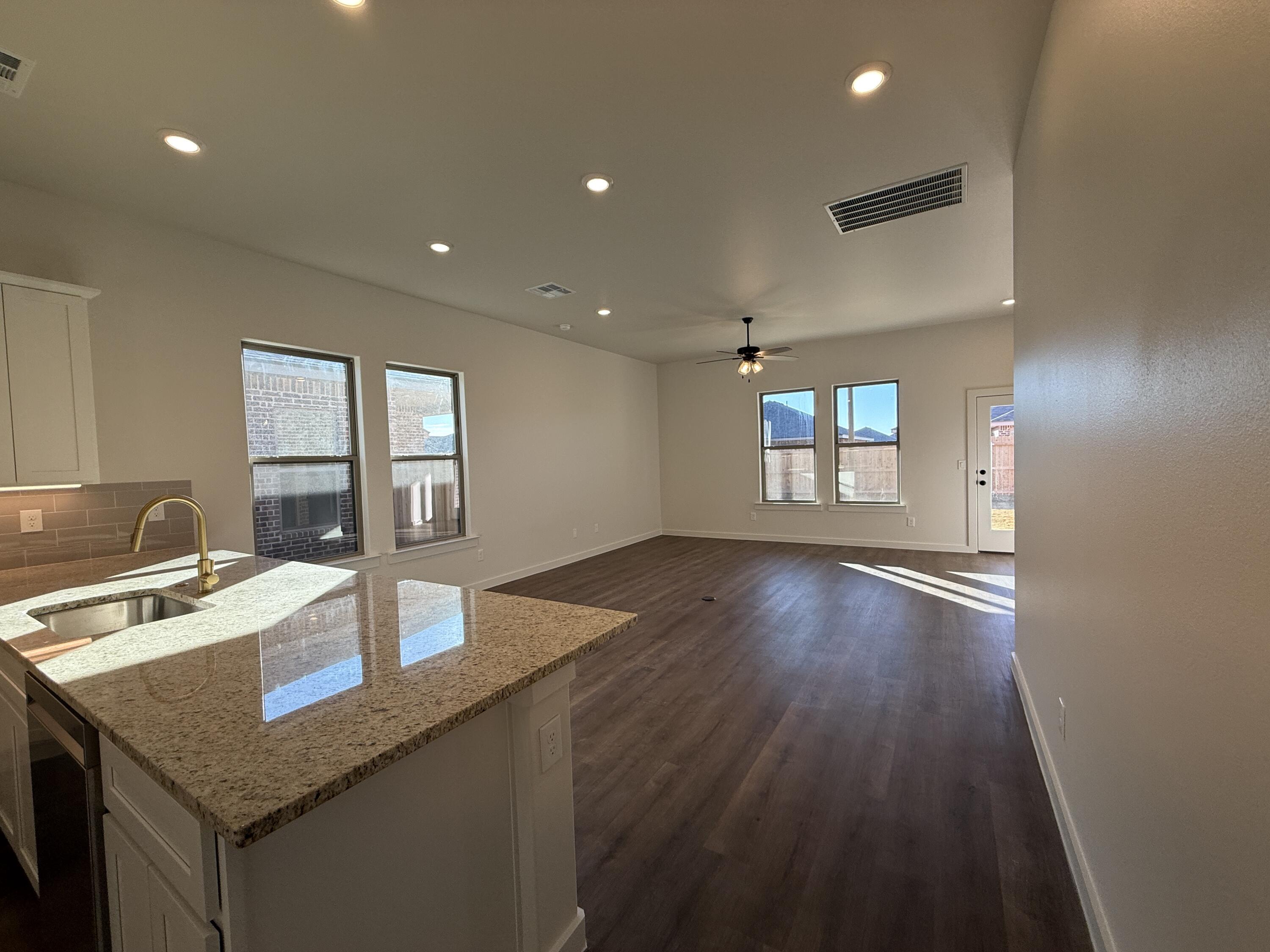 3015 138th Place Lubbock, TX 79423 - Photo 3 of 13 a kitchen with a sink dishwasher a dining table and chairs with wooden floor