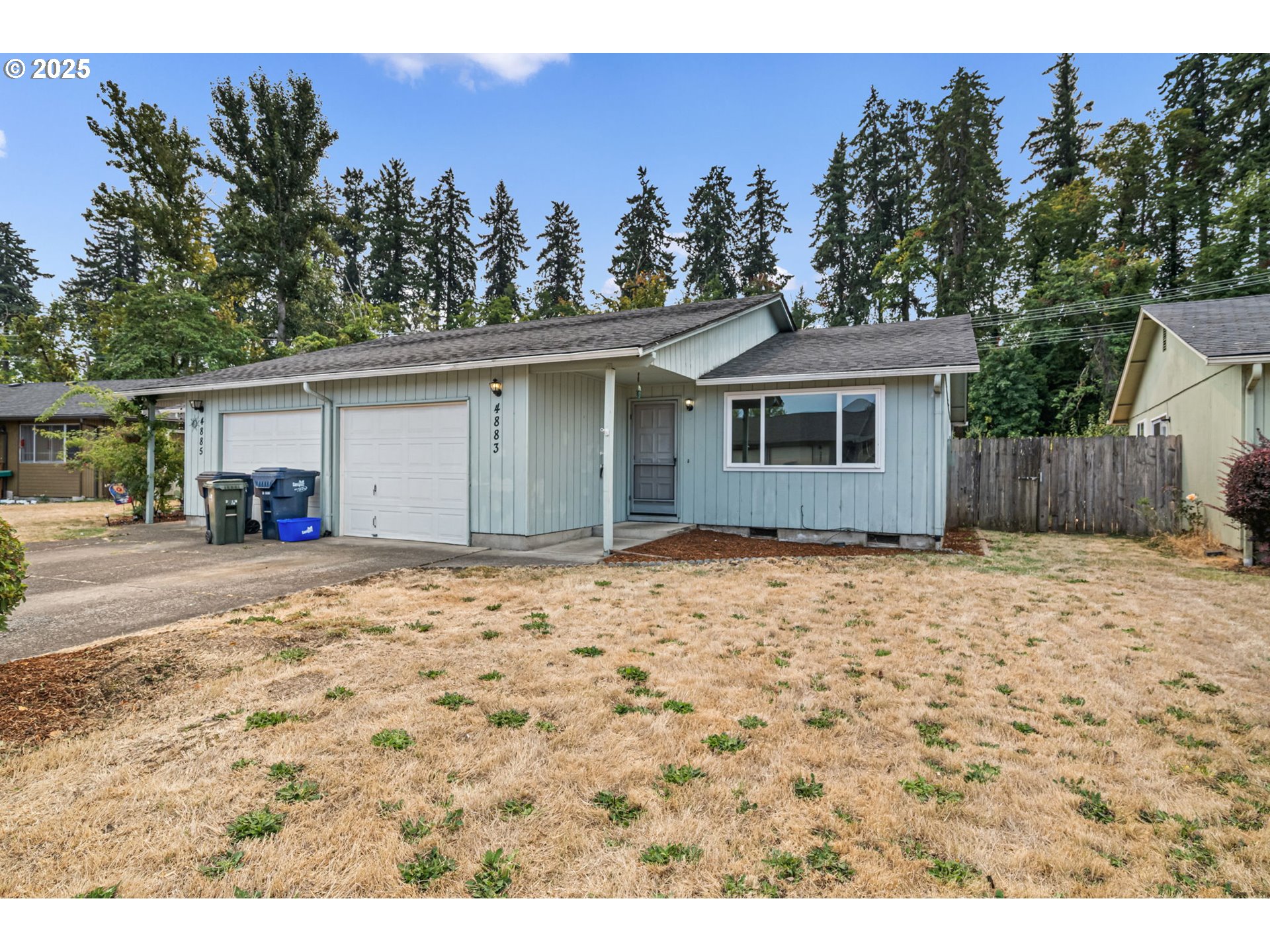 a white house with a large tree in the background
