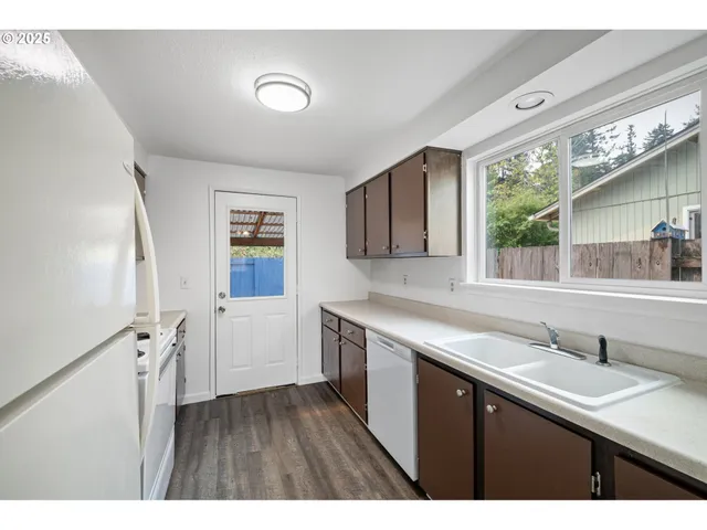 a kitchen with a sink cabinets a window and a wooden floor