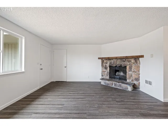 a view of empty room with wooden floor and fireplace