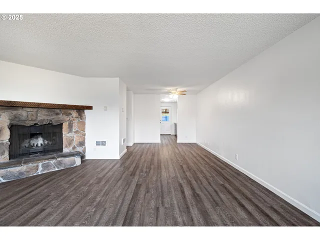 a view of empty room with wooden floor and fireplace