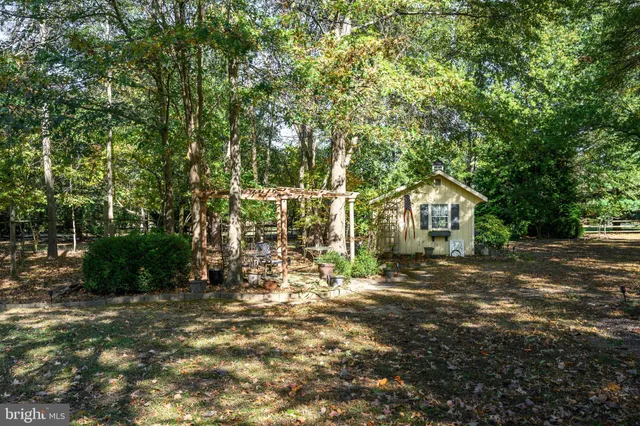 a view of a house with a large tree and sitting area