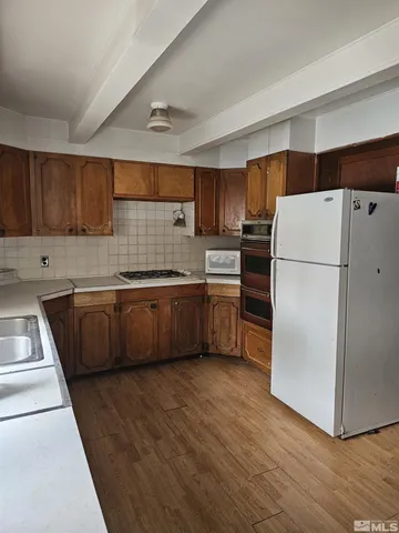 a kitchen with a refrigerator a sink and wooden cabinets