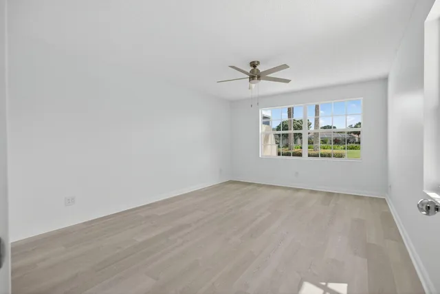 an empty room with windows and ceiling fan