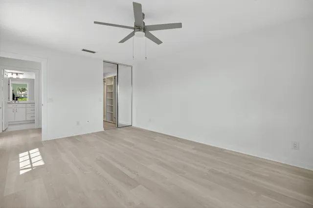an empty room with wooden floor ceiling fan and windows