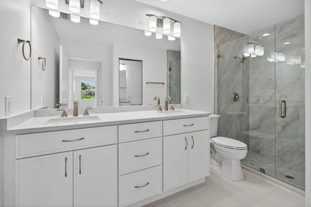 a bathroom with a double vanity sink mirror and toilet