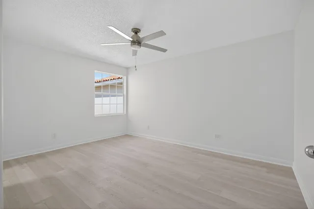 an empty room with windows and fan