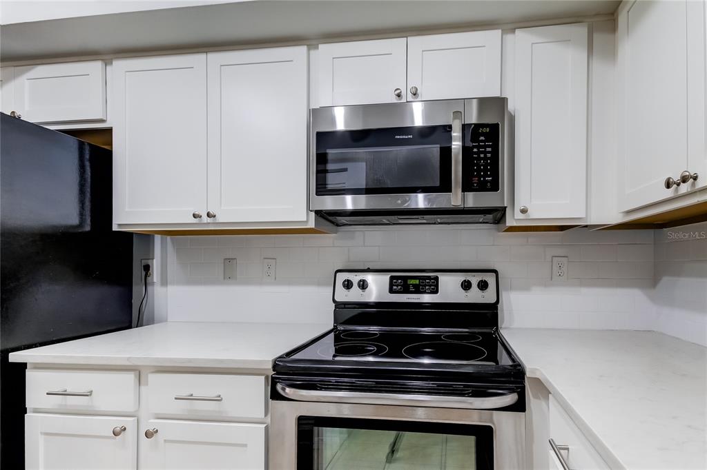 1801 East Lake Road South, Unit 12C Palm Harbor, FL 34685 - Photo 21 of 24 a kitchen with stainless steel appliances granite countertop white cabinets and a stove a oven with white countertops