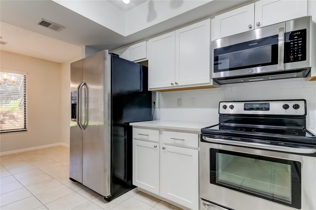1801 East Lake Road South, Unit 12C Palm Harbor, FL 34685 - Photo 22 of 24 a kitchen with cabinets stainless steel appliances and wooden cabinets