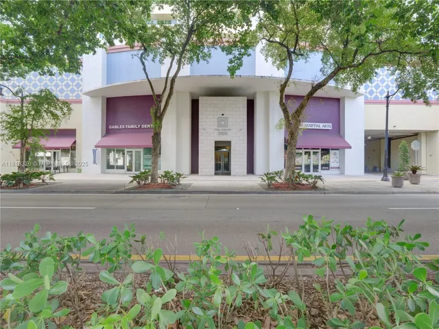 a front view of a building with garden and trees
