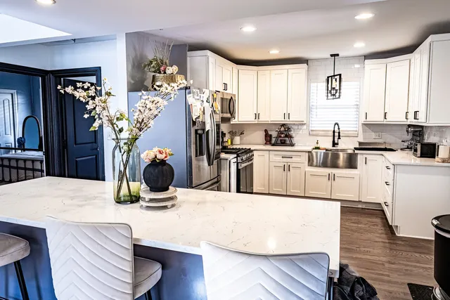 a kitchen with stainless steel appliances kitchen island granite countertop a sink a stove and wooden floor