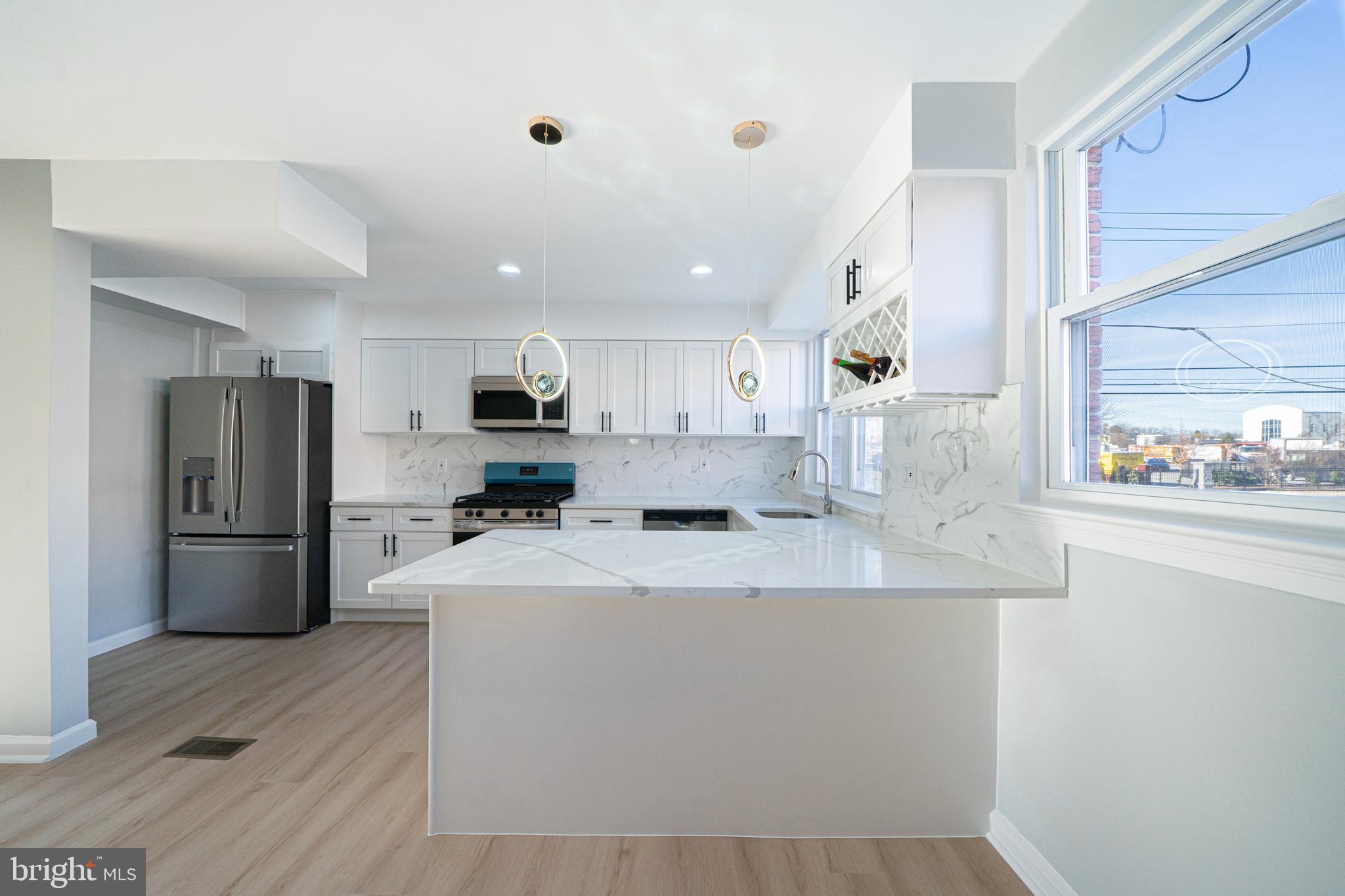 8659 Fayette Street Philadelphia, PA 19150 - Photo 19 of 47 a large kitchen with stainless steel appliances granite countertop a refrigerator a sink a stove and white cabinets with wooden floor