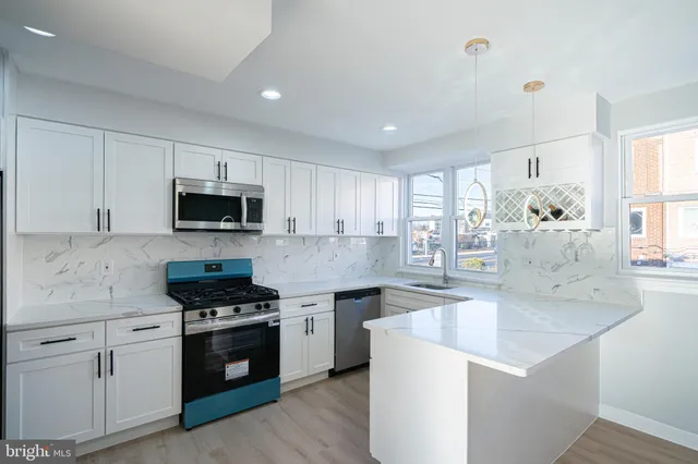 a kitchen with stainless steel appliances white cabinets and wooden floor