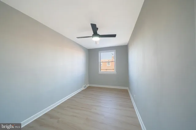 an empty room with a window and a fan