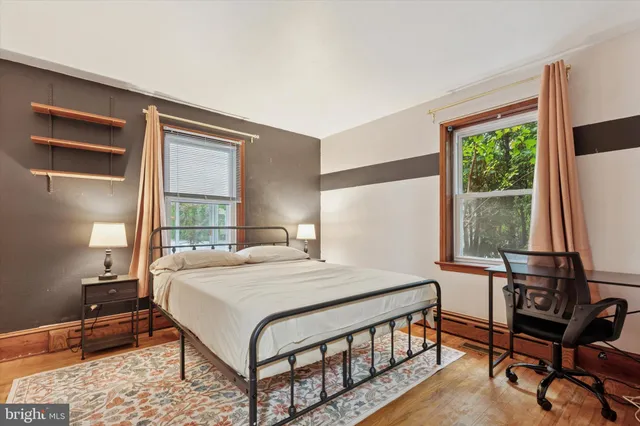 a bedroom with a bed a chair and a large window