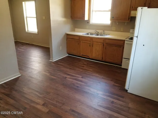 an empty room with wooden floor and window