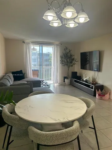 a room with dining table a chandelier a wooden table and chairs