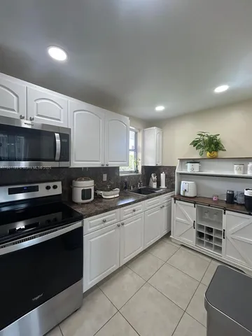 a large white kitchen with stainless steel appliances granite countertop a stove and a sink