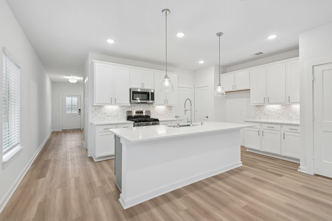 3422 Fresh Bluestream Lane Rosenberg, TX 77471 - Photo 12 of 48 a kitchen with stainless steel appliances kitchen island granite countertop a sink a stove a refrigerator and white cabinets with wooden floor