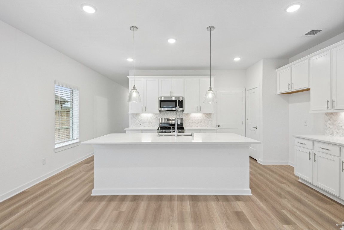 3422 Fresh Bluestream Lane Rosenberg, TX 77471 - Photo 21 of 48 a large white kitchen with kitchen island a stove a sink dishwasher and a refrigerator with wooden floor