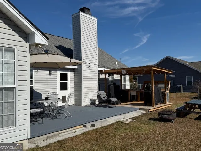 a view of a patio with table and chairs with a barbeque