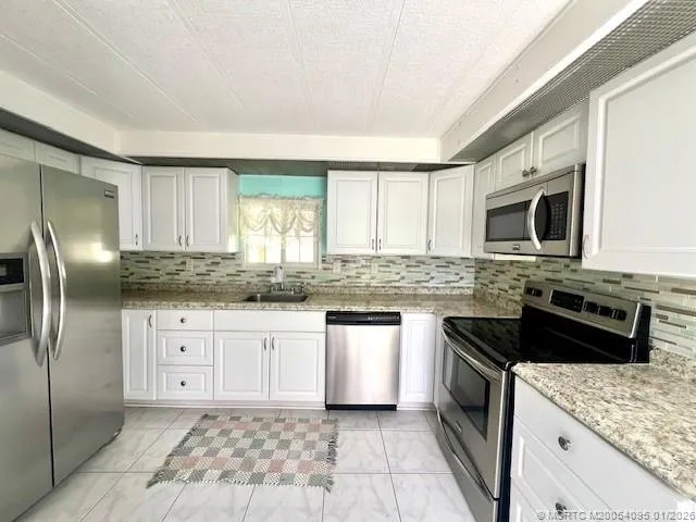 a kitchen with granite countertop a sink stove and refrigerator